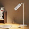 Modern white LED desk lamp illuminating workspace with sleek design for efficient task lighting. Ideal for home offices.