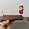 Cute figurine on a wooden base with a balancing toy design, featuring a playful character in a red outfit.